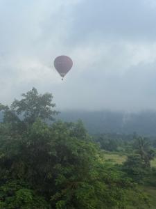 a hot air balloon is flying over trees at The Big Brother Mouse Hostel in Vang Vieng