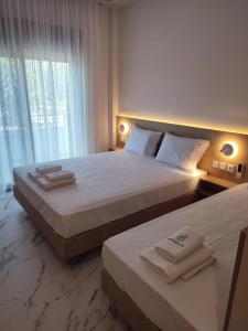 two beds in a hotel room with towels on them at Estelle Hotel in Gerakini