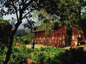 a red building with trees in front of it at Mvubu Falls Lodge in Lobamba