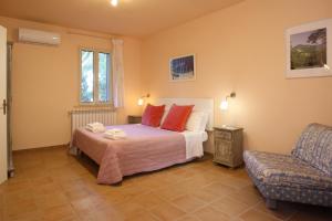a bedroom with a bed with red pillows and a chair at Agriturismo Peretti in Fonteblanda