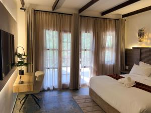 a bedroom with a bed and a chair and windows at Mvubu Falls Lodge in Lobamba