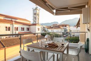 a table and chairs on a balcony with a clock tower at Boheme Apartment in Leptokarya
