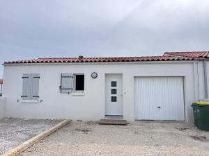 a white house with two garage doors and a garbage can at Ideal pour un couple in Saint-Georges-dʼOléron