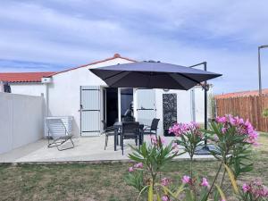 a patio with a table and an umbrella at Ideal pour un couple in Saint-Georges-dʼOléron