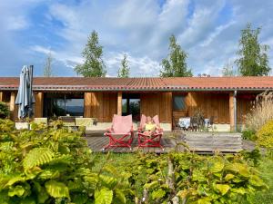a patio with two chairs and a house at Gîte de groupe et charmant cottage L'Agnel in Domaize