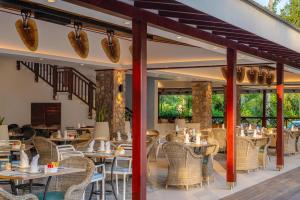 a restaurant with tables and chairs and windows at Paradise Sun Hotel Seychelles in Baie Sainte Anne
