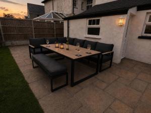 a wooden table with chairs and wine glasses on a patio at Bryniau in Pwllheli
