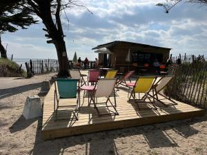 a group of chairs sitting on a deck near the beach at L échappée bêle in Le Val-Saint-Père