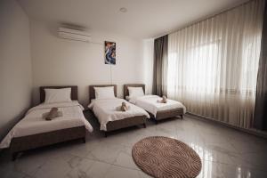 a bedroom with two beds and a large window at Dea Apartments - Peja in Peje