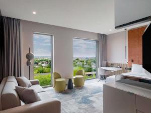 a living room with a couch and a table with chairs at Mercure Oradea in Oradea