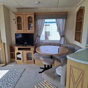 a caravan living room with a table and a tv at Atlas Florida in Ingoldmells +5 photos