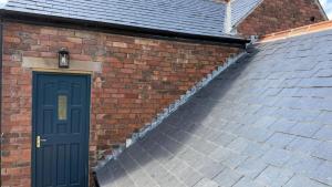 a brick building with a blue door and stairs at Holt Hall - First Floor Apartment in Matlock