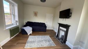 a living room with a blue couch and a fireplace at Holt Hall - First Floor Apartment in Matlock