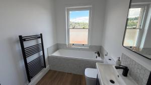 a bathroom with a bath tub and a sink at Holt Hall - First Floor Apartment in Matlock +7 photos