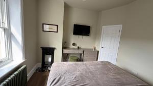 a bedroom with a bed and a tv on the wall at Holt Hall - First Floor Apartment in Matlock