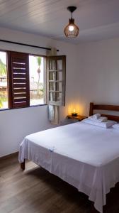 a bedroom with a large white bed and a window at Pousada Ventos do Guajiru-Casa de Kitesurfistas in Itarema