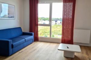 a living room with a blue couch and a large window at Studio for 2 in La Teste-de-Buch parking in La Teste-de-Buch