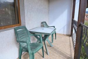 zwei grüne Stühle und ein Tisch auf einem Balkon in der Unterkunft Кирицова Къща in Bansko