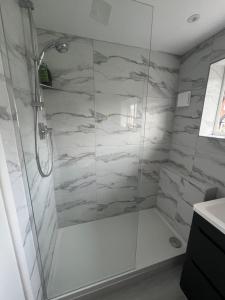a bathroom with a shower with white marble walls at Beach House Manningtree in Manningtree +26 photos