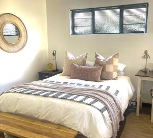 a bedroom with a bed with pillows and a mirror at Nahoon Studio B in East London