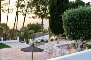 a garden with an umbrella and stairs and trees at Finca La Oliveta Ronda in Ronda