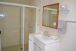 ein weißes Bad mit einem Waschbecken und einer Dusche in der Unterkunft Gatton Motel in Gatton