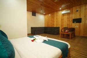 a bedroom with a bed and a couch and a television at Vasant Corbett Resort By Mannat in Rāmnagar