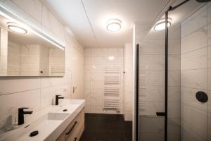 a white bathroom with a shower and a sink at Penthouse Ostrea 60 in Nes +13 photos