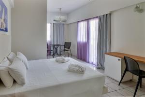 a bedroom with a white bed and a table and chairs at Sunny Vibes by Estia Adults Only in Stalís