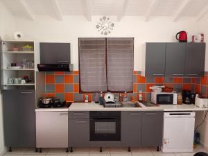 a kitchen with gray cabinets and a sink in it at Chambre d'hôtes du Moulin SPA in Sainte-Anne