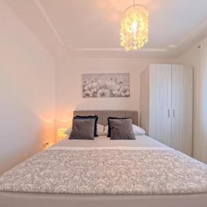 a bedroom with a large bed and a chandelier at CASA di NATALIA, Spacious 2BR Apartment for 6 near Beach ,Free Parking in Kaštela