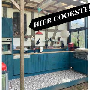 a kitchen with blue cabinets and a sign that reads her cookstration at Bauwagen im Apfelgarten in Winsen