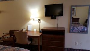 a hotel room with a desk and a bed and a mirror at Innkeeper Motel Hamel in Hamel