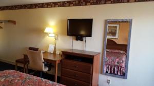 Habitación de hotel con escritorio, cama y espejo en Innkeeper Motel Hamel en Hamel