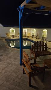 a swimming pool with chairs and a bench and a table at Villa Syrine Djerba in Al Ḩaddādah
