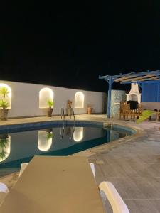 a swimming pool at night with a table and chairs at Villa Syrine Djerba in Al Ḩaddādah