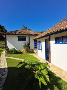 a white house with a grass yard and a house at Pousada chalés São Geraldo in Lima Duarte