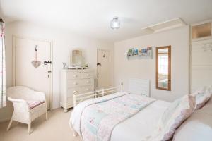 a white bedroom with a bed and a dresser at Fishermans Cottage, Aldeburgh in Aldeburgh