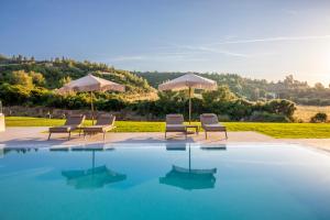 a swimming pool with chairs and umbrellas next to at Kallies villas with shared Pool in Pefkochori +158 photos