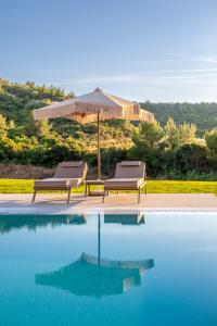 two chairs and an umbrella next to a swimming pool at Kallies villas with shared Pool in Pefkochori