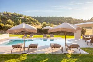 a swimming pool with chairs and umbrellas at Kallies villas with shared Pool in Pefkochori