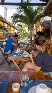 a group of people sitting at a table at a restaurant at Pousada Ventos do Guajiru-Casa de Kitesurfistas in Itarema