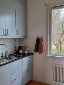 a kitchen with white cabinets and a sink and a window at Det Gamla Postkontoret in Råda