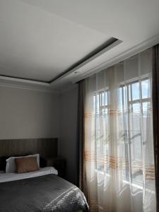 a bedroom with a bed and a large window at Noble Park Apartment in Kiserian