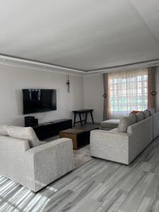 a living room with two couches and a flat screen tv at Noble Park Apartment in Kiserian +9 photos