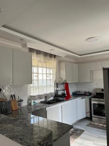 a kitchen with white cabinets and granite counter tops at Noble Park Apartment in Kiserian