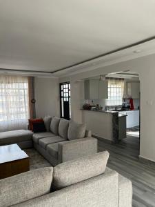 a living room with a couch and a kitchen at Noble Park Apartment in Kiserian