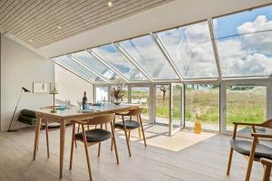 a dining room with a table and chairs and glass windows at BL1001-Blokhus-Ferren-95 in Blokhus