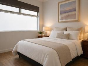 a bedroom with a large white bed and a window at Sundown terrace in North Fremantle