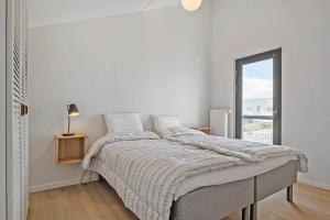a white bedroom with a large bed and a window at BL1001-Blokhus-Ferren-95 in Blokhus